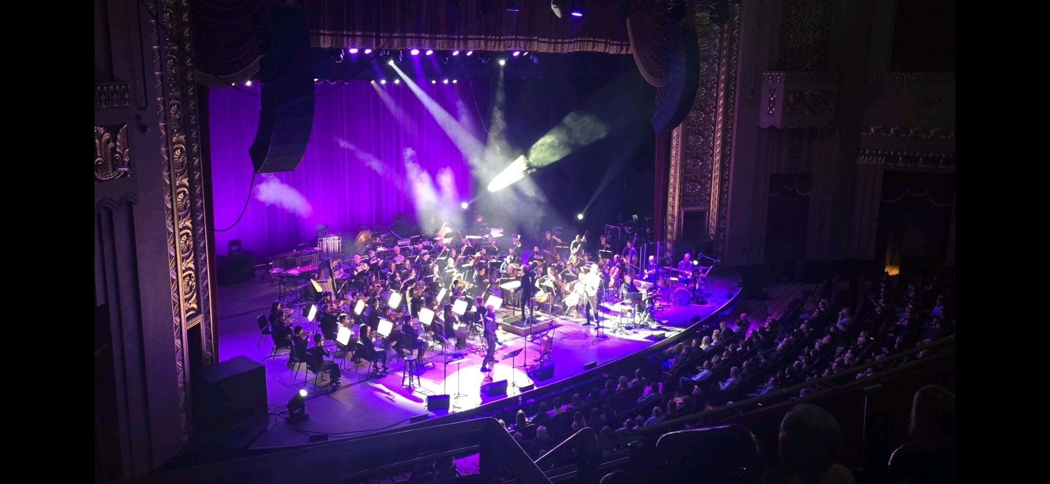 Wide balcony view of the Adam Wainwright concert with orchestra, stage lighting, and audience at Stifel Theatre