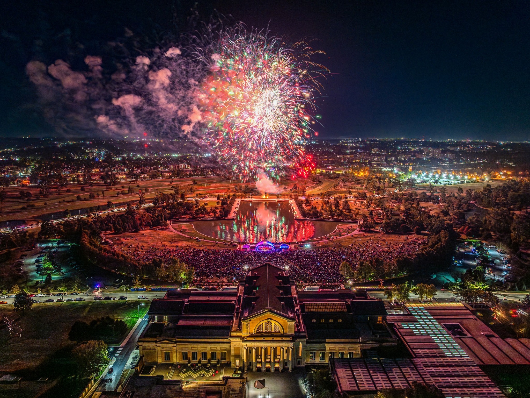 Fireworks above a large outdoor symphony audience and stage on Art Hill